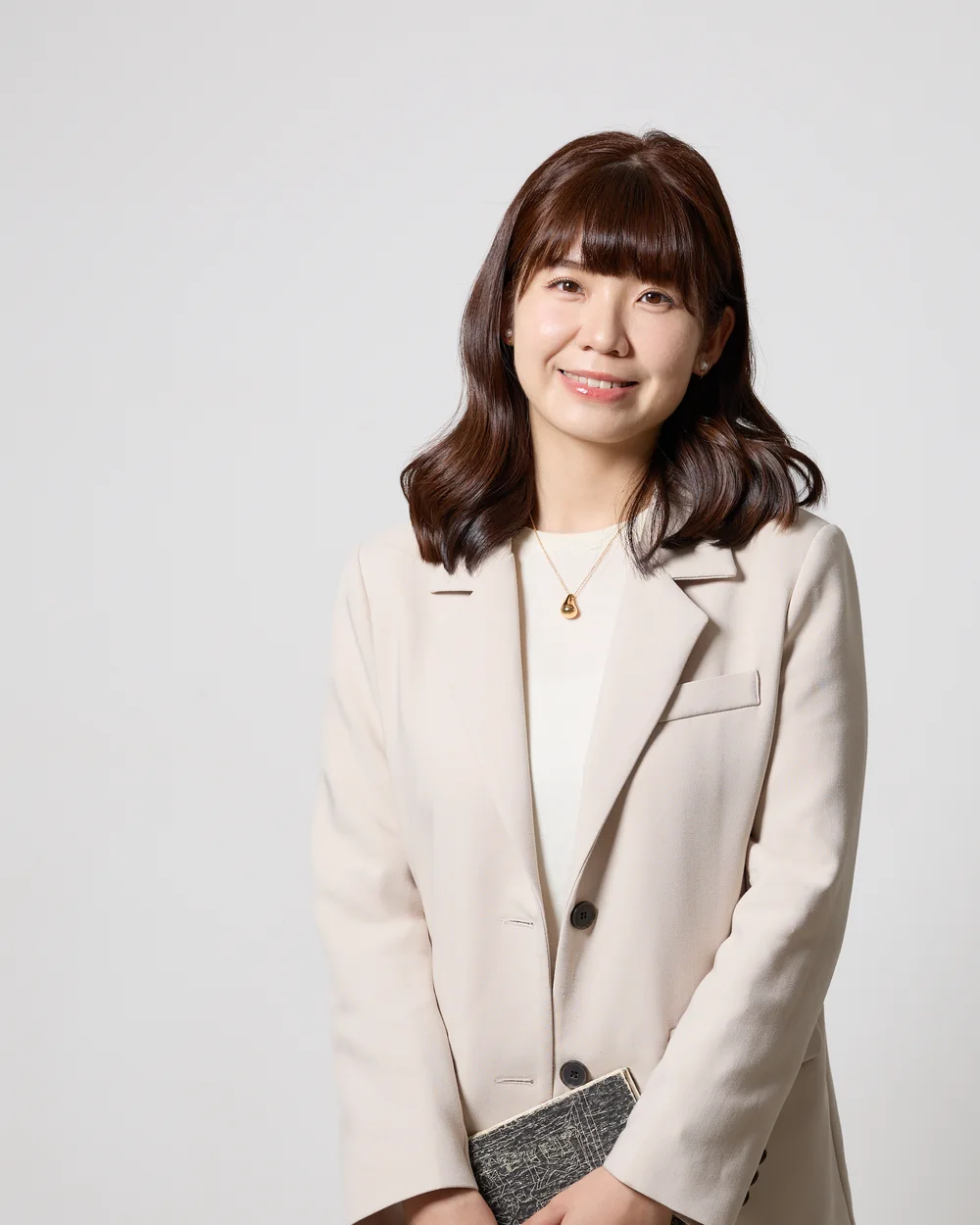 Jeany 手拿筆記本與筆,面帶溫暖笑容
